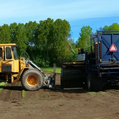 Två maskiner som skördar rullgräs på Gräscenters egna gräsodling.