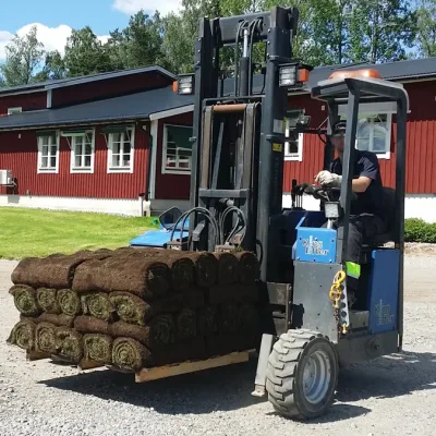 Trucklossning färdig gräsmatta. Trucken har en pall med gräsmatta på smårulle.